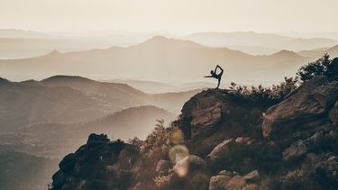 iemand doet yoga pose op berg