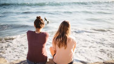 Twee vriendinnen zitten op het strand