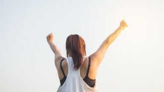 Vrouw in sportkleding die armen in de lucht steekt