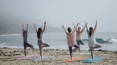 vrouwen doen yoga op het strand