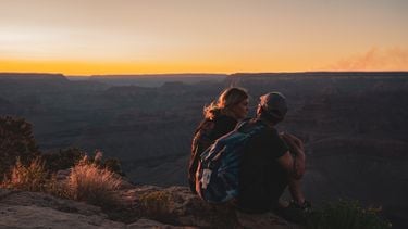 Te hoge verwachtingen relatie, stel zit op een rots te kijken naar de zonsondergang