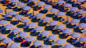 Strand bezaaid met bedjes en parasollen