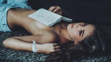 vrouw ligt topless op de grond met boek op haar borst