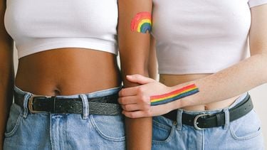 Vrouwen houden elkaar vast met regenboog op de arm