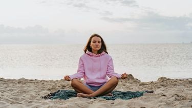 meisje mediteert op strand