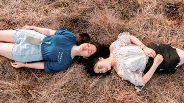 Twee meisjes liggen in het gras