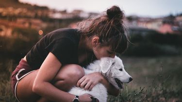 meisje knuffelt en kust haar hond
