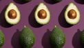 halve en hele avocado's op paarse achtergrond