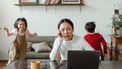 Vermoeide vrouw die thuiswerkt met twee kinderen