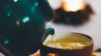 Theepot schenkt thee in een theemok