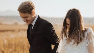 getrouwd koppel loopt hand in hand door een graanveld