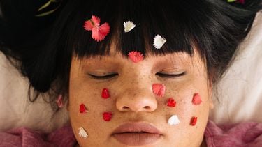 vrouw met rozenblaadjes op gezicht