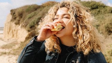 gezonde relatie met voeding, vrouw eet boterham op strand