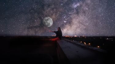 Meisje zit op dak met volle maan en sterren op de achtergrond