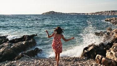 vrouw loopt op rotsen bij zee