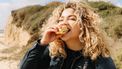 gezonde relatie met voeding, vrouw eet boterham op strand