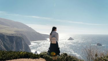 vrouw met backpack aan de kust