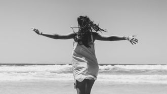 vrouw is blij en loopt over het strand