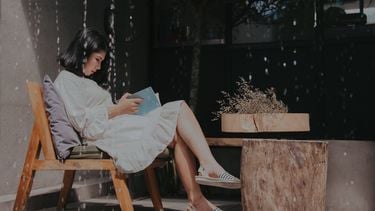 vrouw die alleen een boek leest in een café