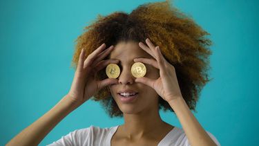 vrouw heeft 2 bitcoins vast voor haar ogen
