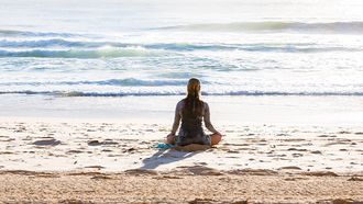 meisje doet kundalini yoga op strand