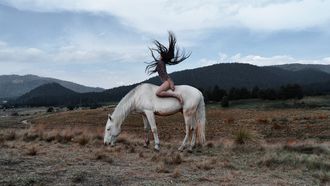 vrouw zit op paard en gooit haar haren los