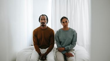 vrouw en man zitten op de rand van een bed